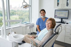 Happy senior patient sitting in a dentist chair, representing coverage under the Canadian Dental Care Plan.